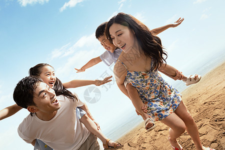 幸福的一家四口在沙滩上玩耍图片