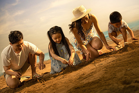 快乐的四口之家在沙滩上玩沙子图片