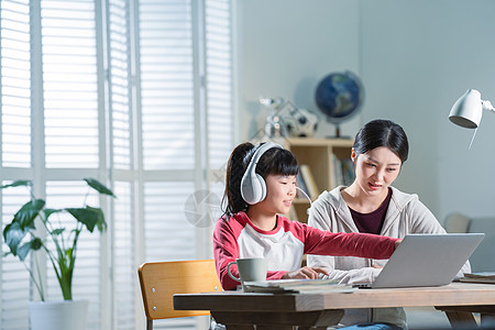 年轻妈妈辅导女儿上网课图片