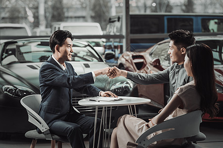 高档椅子汽车销售人员和青年夫妇握手背景