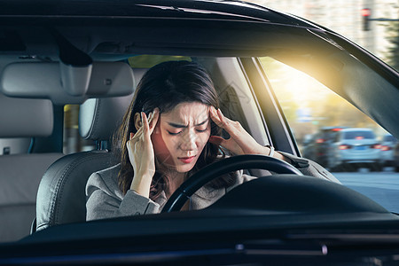 头痛的青年女人驾驶汽车图片