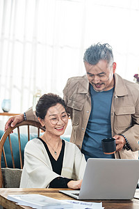 家科技幸福的中老年夫妇在家使用笔记本电脑背景