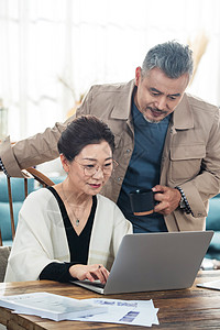网上幸福的中老年夫妇在家使用笔记本电脑背景