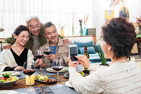 聚餐时快乐的中老年人用手机拍照图片