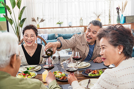 聚餐时中年男士给朋友倒红酒高清图片