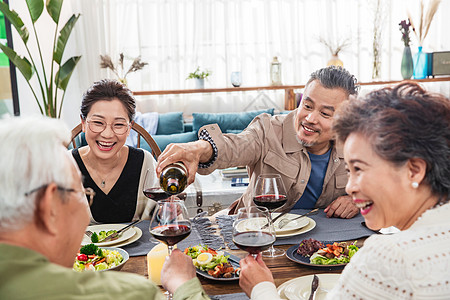 聚餐时中年男士给朋友倒红酒高清图片