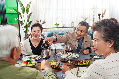 聚餐时中年男士给朋友倒红酒高清图片