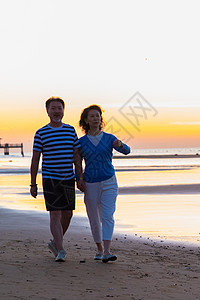 夕阳海景老年夫妇在海边散步背景