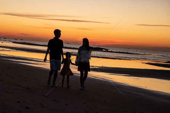 夕阳下一家三口在海边玩耍图片