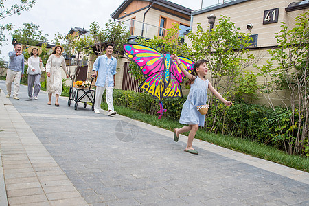 拿着风筝的小女孩和家人在户外玩耍图片