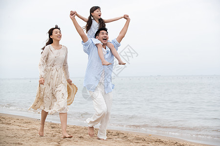 背着孩子的妈妈幸福的一家三口在海边玩耍背景