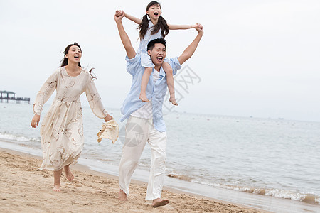 幸福的一家三口在海边玩耍图片