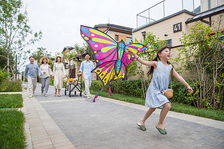 风筝和小女孩拿着风筝的小女孩和家人在户外玩耍背景