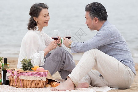 沙滩红酒幸福的老年夫妇坐在海滩上野餐饮酒背景