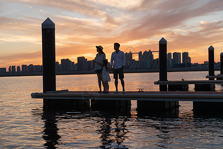 黄昏海景夕阳下一家三口在海边玩耍背景