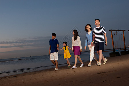 夕阳下在海边散步的幸福家庭高清图片