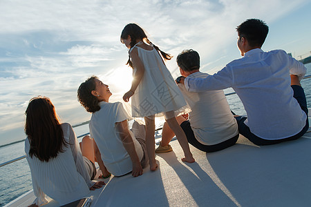 黄昏海景夕阳下坐在游艇上的快乐一家人背景