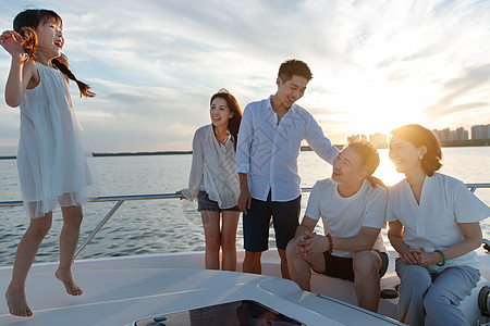 黄昏海景夕阳下在游艇上的快乐一家人背景
