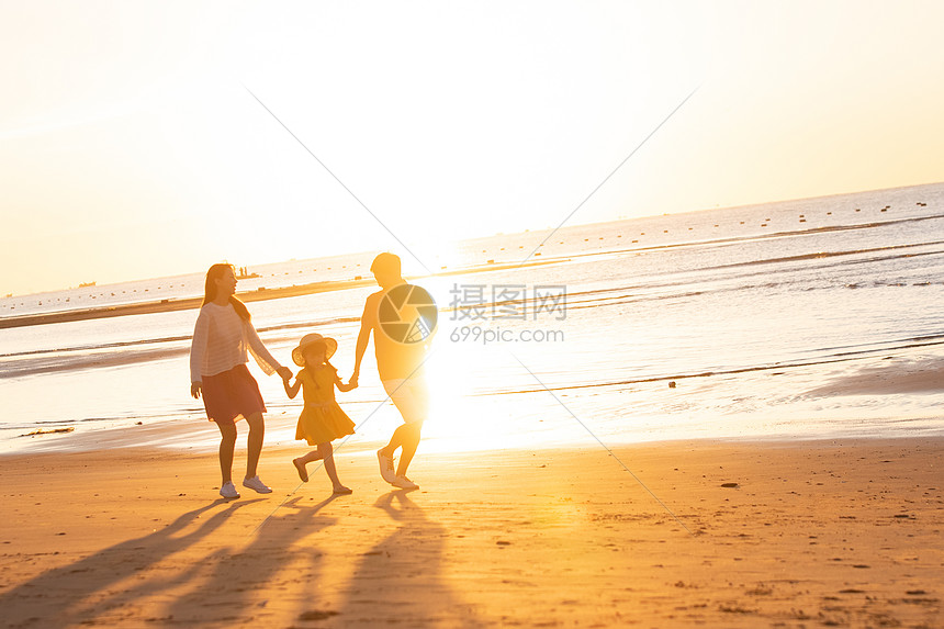 夕阳下一家三口在海边玩耍图片