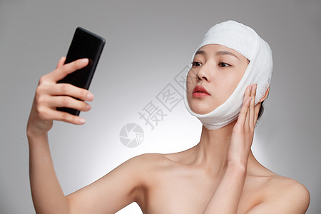 头戴绷带的漂亮女人用手机视频图片