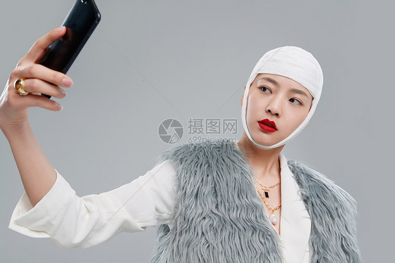 头戴绷带的漂亮女人用手机视频图片