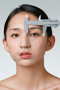 整形医生用卡尺测量青年女人面部图片