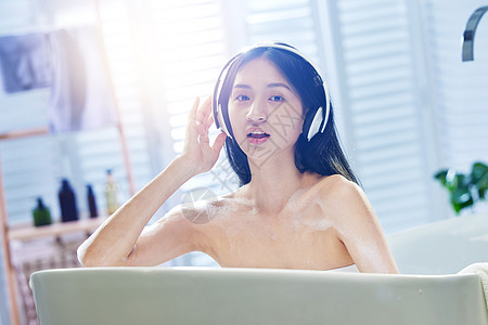 浴缸内听音乐的年轻女孩高清图片