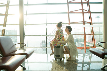 年轻妈妈和女儿从机场候机厅往外看图片