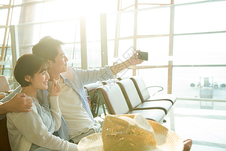 青年情侣坐在机场候机厅看手机图片