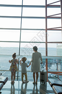 年轻妈妈和孩子在机场候机厅往外看图片