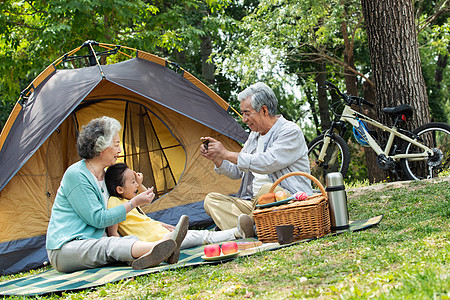 老年夫妇带着孙女在公园里郊游帐篷高清图片素材