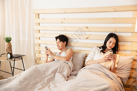 年轻情侣在床上使用手机图片