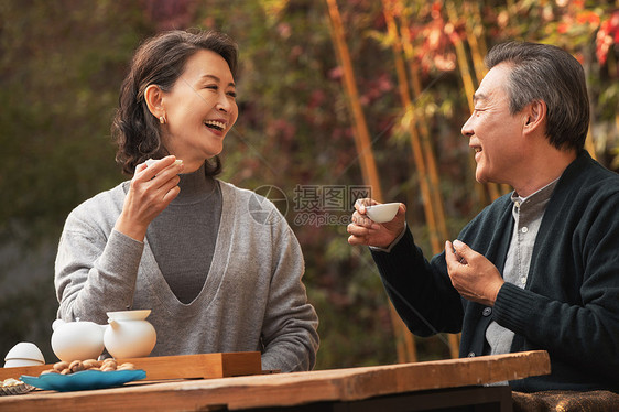 快乐的老年夫妇在庭院内品茶图片