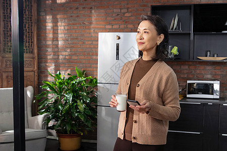 快乐的老年女人拿着手机和牛奶图片