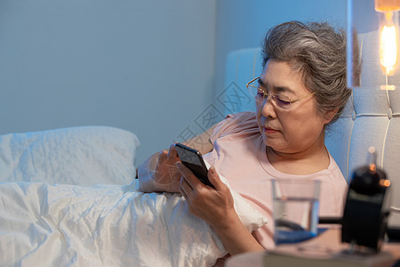 老年人坐在床上看手机图片