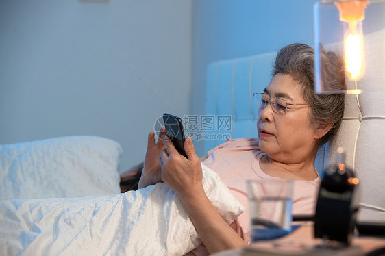 老年人坐在床上看手机图片