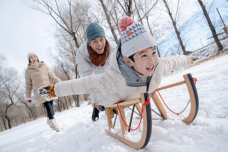 在雪地上玩雪橇的一家人图片