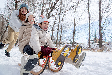 在雪地上玩雪橇的一家人图片