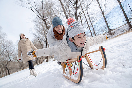 趴着玩在雪地上玩雪橇的一家人背景