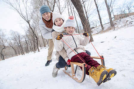 在雪地上玩雪橇的一家人图片