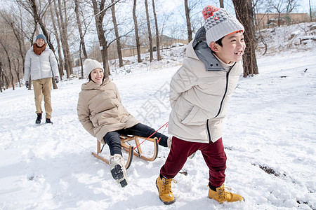 在雪地上玩雪橇的一家人图片