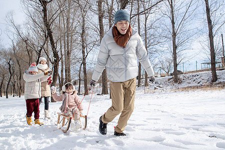 欢乐家庭在雪地上玩雪橇图片
