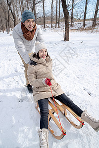青年夫妇在雪地上玩雪橇图片
