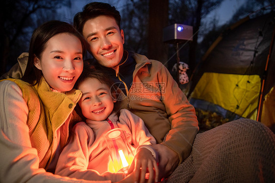 幸福的一家三口夜晚在野外露营图片
