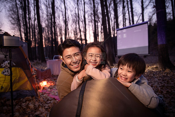 幸福的父亲和两个孩子夜晚野外露营图片