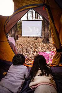 看电影背影户外露营的儿童趴在帐篷里看电影背景