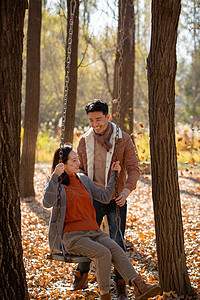 户外秋天幸福的夫妇在荡秋千图片