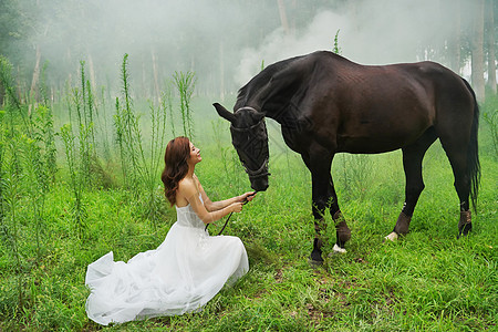 草地上穿婚纱的青年女人牵着马图片