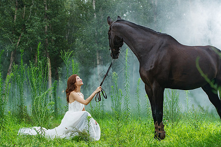 草地上穿婚纱的漂亮年轻女人和马图片