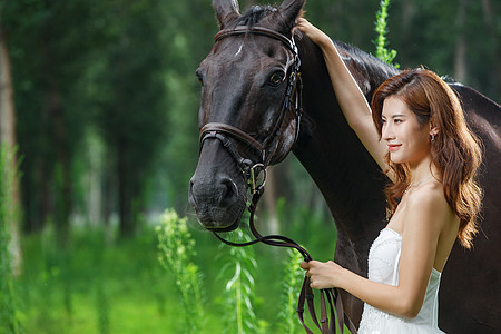 树林里漂亮的青年女人牵着马图片